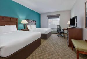 a hotel room with two beds and a desk at Baymont Inn & Suites by Wyndham Glen Rose in Glen Rose