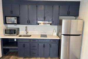 cocina con armarios azules y nevera de acero inoxidable en Ramada by Wyndham Studio Suites Dothan en Dothan