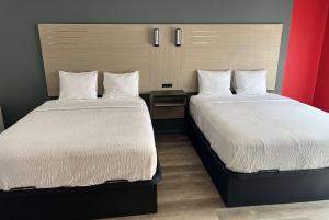 twee bedden naast elkaar in een kamer bij Ramada by Wyndham Studio Suites Dothan in Dothan