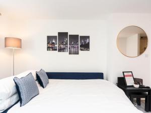 um quarto com uma cama branca e um espelho em Pass the Keys Fresh and Stylish Central Flat With Parking and Garden em Londres