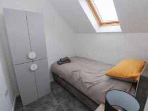 um pequeno quarto com uma cama e uma janela em The Loft Wisteria Cottage em Saundersfoot