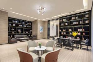 a library with chairs and tables and bookshelves at Ramada Encore by Wyndham Kunming Guandu in Kunming