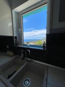 a kitchen sink with a window with a view of the ocean at Endless blue Apartments in Dhërmi