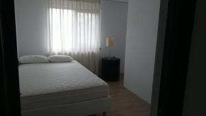a white bedroom with a bed and a window at Vila Flight in Aroneanu