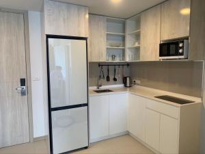uma cozinha com armários brancos e uma porta de vidro deslizante em Apartments in Skypark Laguna Bang Tao em Praia de Bang Tao