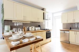 a kitchen with white cabinets and a wooden counter top at Tintern Apartment - Clapham in London