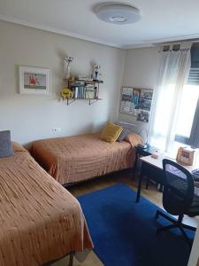 1 dormitorio con 2 camas y escritorio con silla en Casa en la ciudad. en Ourense