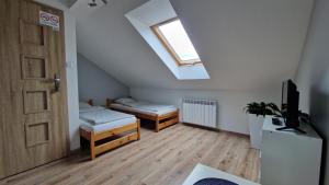 a attic room with two beds and a window at Vip Village in Miedzierza