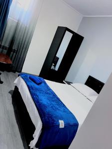 a bedroom with a bed with a blue blanket on it at Hotel Sunny in Akhaltsikhe