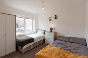 um quarto com 2 camas e uma janela em Spacious home close to city centre location em Leeds