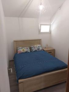 1 dormitorio con cama con sábanas azules y ventana en T3 2 chambres plus mezzanine Saint leu 3mn à pied du lagon, en Saint-Leu