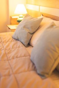 a bed with white pillows and a lamp on a table at APARTAMENTO CENTRICO 2 DORMITORIOS AMPLIO BALCON con OPCION COCHERA in Neuquén