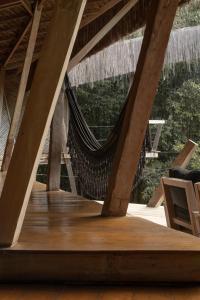 a hammock hanging from a roof with a chair at KA BRU Forest Villa in Itacaré