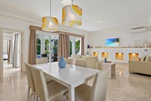 uma sala de jantar e sala de estar com uma mesa branca e cadeiras em Privè Royal Villa Bahiazul em Corralejo