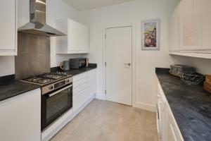 a kitchen with white cabinets and a stove top oven at Host & Stay - Rochester Apartment in Rochester