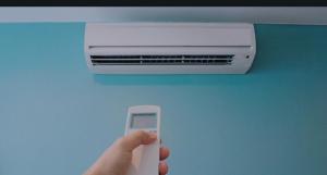 a person holding a remote control in front of an air conditioner at Pensaò Big Game Maio in Vila do Maio