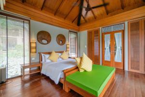 - une chambre avec un lit et un banc vert dans l'établissement Pattara Resort & Spa, à Phitsanulok