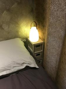 une lampe assise sur une table de nuit à côté d'un lit dans l'établissement Chalet cosy atypique, à Vichy