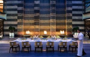 a man standing in front of a table with candles at Bengaluru Marriott Hotel Whitefield in Bangalore