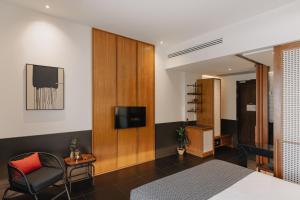 a bedroom with a bed and a tv and a chair at Hotel Loy Chiang Mai in Chiang Mai