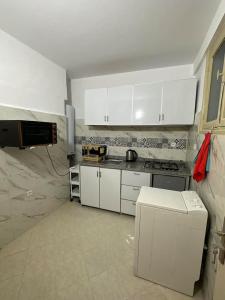 une cuisine avec des placards blancs et un comptoir dans l'établissement Appartement cosy à Rabat, à Rabat