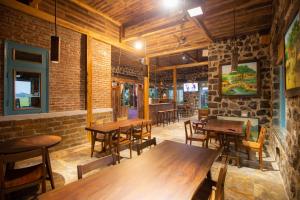 um restaurante com mesas e cadeiras de madeira e uma parede de tijolos em ChezCao Rice Field Ecolodge Ninh Binh em Ninh Binh