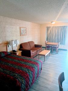 a hotel room with a bed and a couch and a table at Western Inn Lakewood in Lakewood