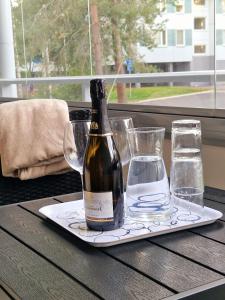 una botella de vino en un plato con vasos en una mesa en Lovely studio apartment, glazed balcony and own parking space, en Hyvinkää