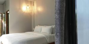 1 cama con sábanas blancas y almohadas en una habitación en Siri Guesthouse @ Surat Thani, en Suratthani