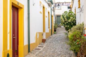 埃武拉的住宿－Casa da Padaria，一座黄色和白色建筑的古镇小巷