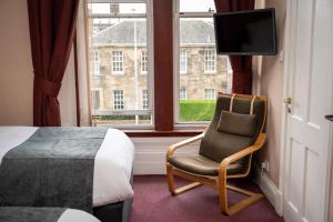 ein Schlafzimmer mit einem Bett, einem Stuhl und einem TV in der Unterkunft Hampton Hotel by Greene King Inns in Edinburgh