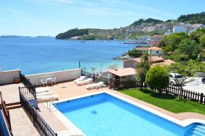 a house with a swimming pool and a view of the water at Apartamentos Sinás Playa in Raxó