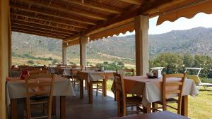 a restaurant with tables and chairs with mountains in the background at Li Teggi Turismo Rurale in San Teodoro