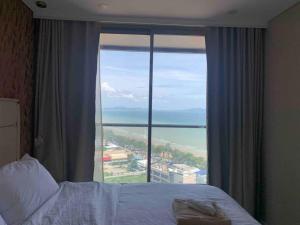 um quarto de hotel com uma cama e uma grande janela em Copacabana Pattaya em Praia de Jomtien