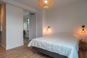 a white bedroom with a bed and a hallway at La Mouette - Appartement à 100m de la plage in Bénodet