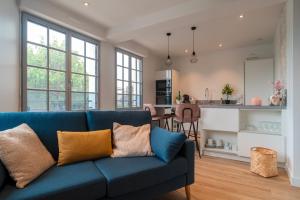 a living room with a blue couch and a kitchen at La Mouette - Appartement à 100m de la plage in Bénodet