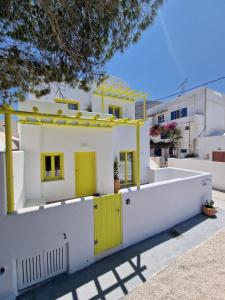 a house with yellow doors and a white fence at New Earth in Kamari