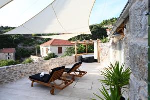 a patio with two lounge chairs and a stone wall at Villa Teza Hvar in Hvar
