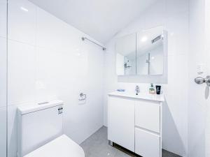 Baño blanco con aseo y lavamanos en Ultimo Terrace Homestay en Sídney