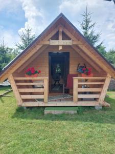 eine Blockhütte mit einer Veranda im Gras in der Unterkunft Căbănuță la Munte cu Piscină in Bistra