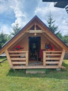 eine große Holzhütte mit einer Veranda auf einem Feld in der Unterkunft Căbănuță la Munte cu Piscină in Bistra