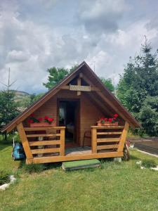 eine kleine Holzhütte mit einer Veranda auf einem Feld in der Unterkunft Căbănuță la Munte cu Piscină in Bistra