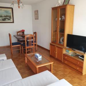 uma sala de estar com uma televisão e uma mesa em Apartamento 100 m playa, Vilagarcía de Arousa. em Vilagarcía de Arousa