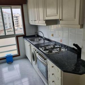 uma cozinha com fogão forno ao lado de um lavatório em Apartamento 100 m playa, Vilagarcía de Arousa. em Vilagarcía de Arousa