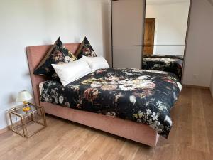 een slaapkamer met een bed met een dekbed met zwarte bloemen bij Au parfum des roses in Gunstett