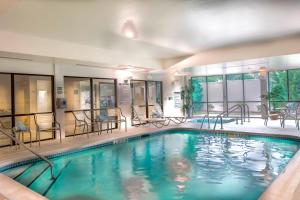 una piscina en un hotel con sillas y mesas en Courtyard Greensboro Airport, en Greensboro