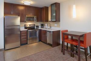 a kitchen with stainless steel appliances and a wooden table at Residence Inn by Marriott Chicago Bolingbrook in Bolingbrook