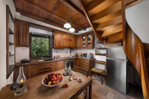 a kitchen with wooden cabinets and a bowl of fruit on a table at VILLA PALIOS STATHMOS in Mileai
