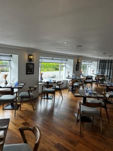 a dining room with tables and chairs and windows at The Airds Hotel and Restaurant in Port Appin