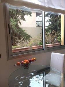 - un bol de fruits sur une table en verre devant une fenêtre dans l'établissement Appartamento "Renata" in residence Cap Roux Eze Borde de Mer Costa Azzurra, à Èze